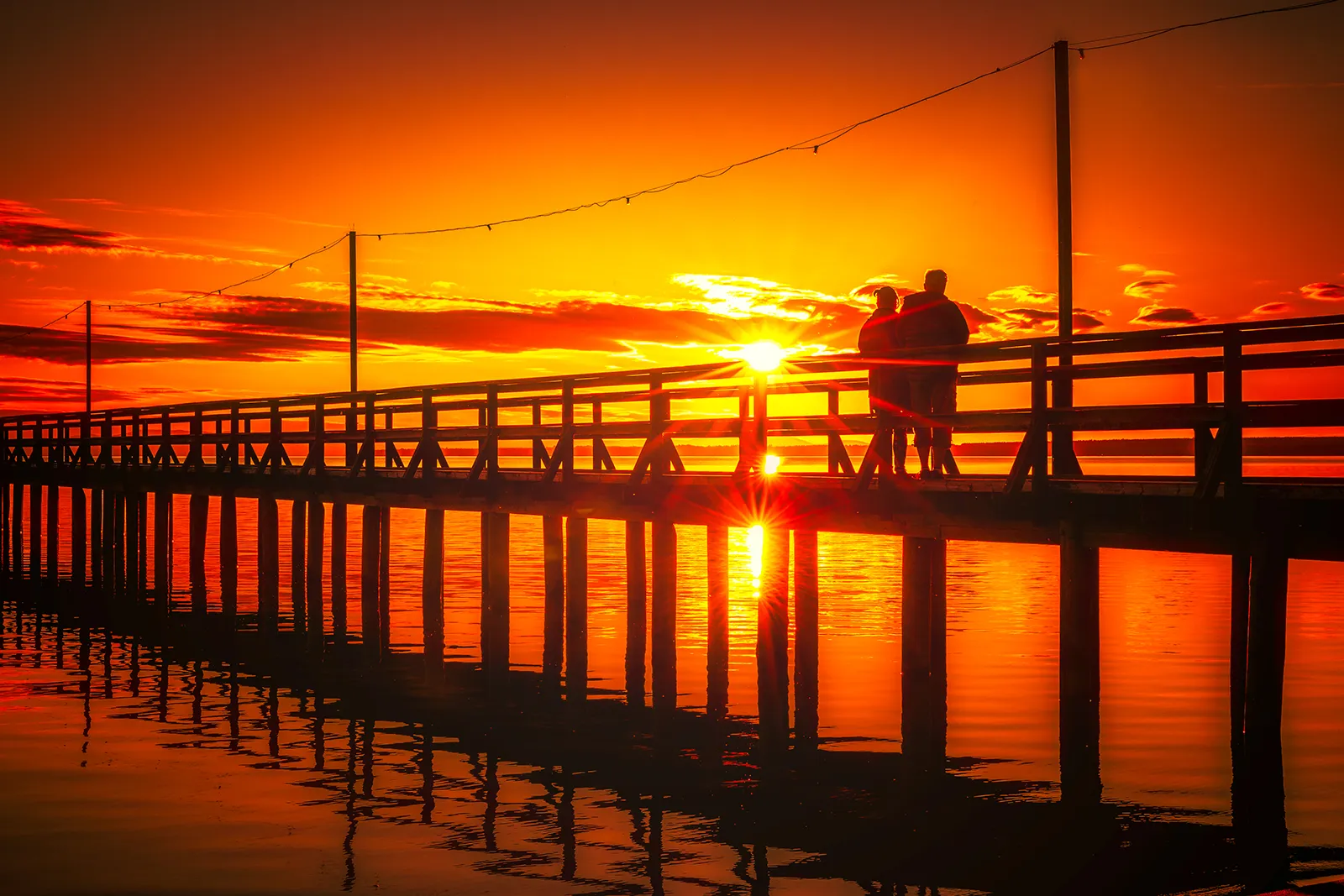 Solnedgång med siluetter på Långbryggan i Rättvik