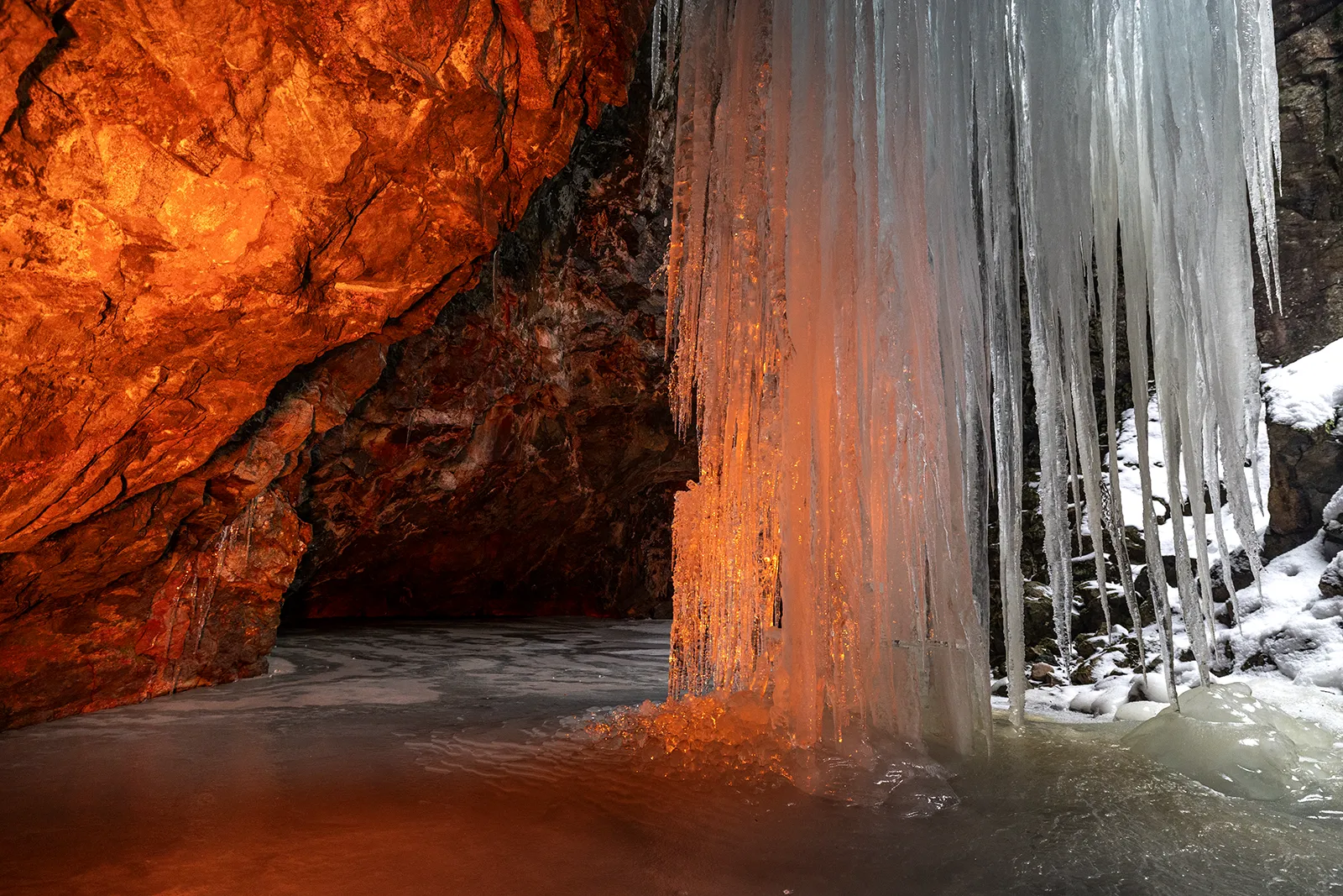 Orange LED-ljus på långa istappar i grotta