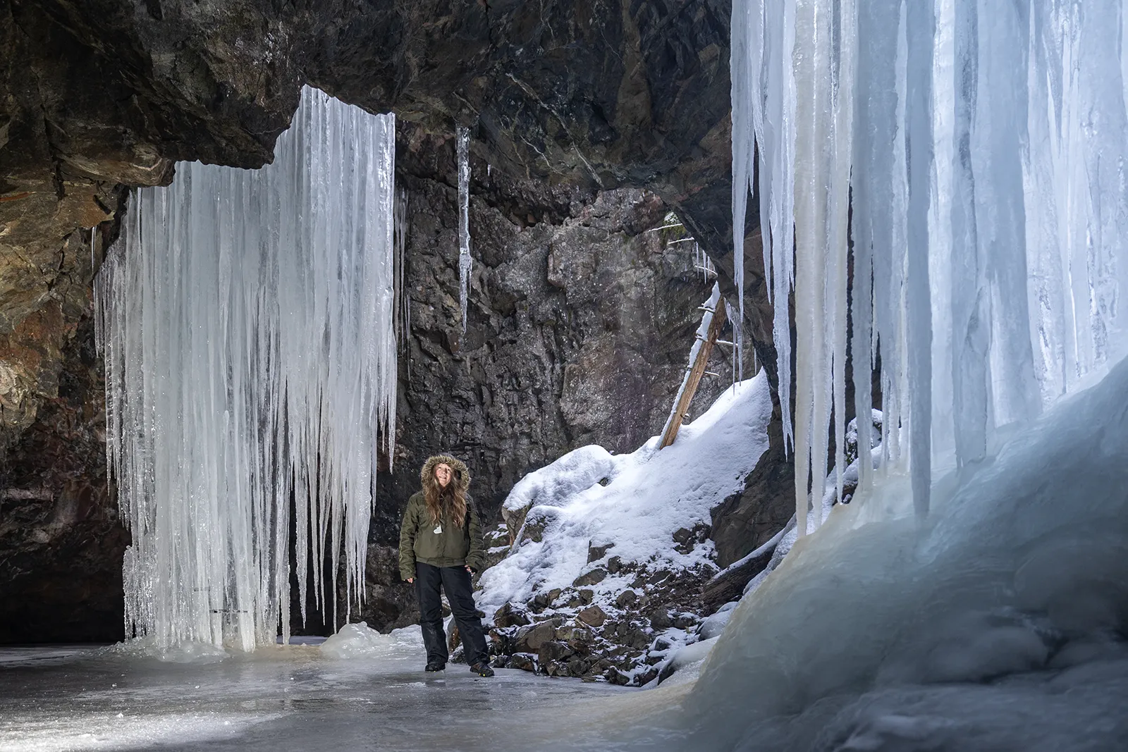 Människa framför jättelika istappar i Skommartjärns gruva