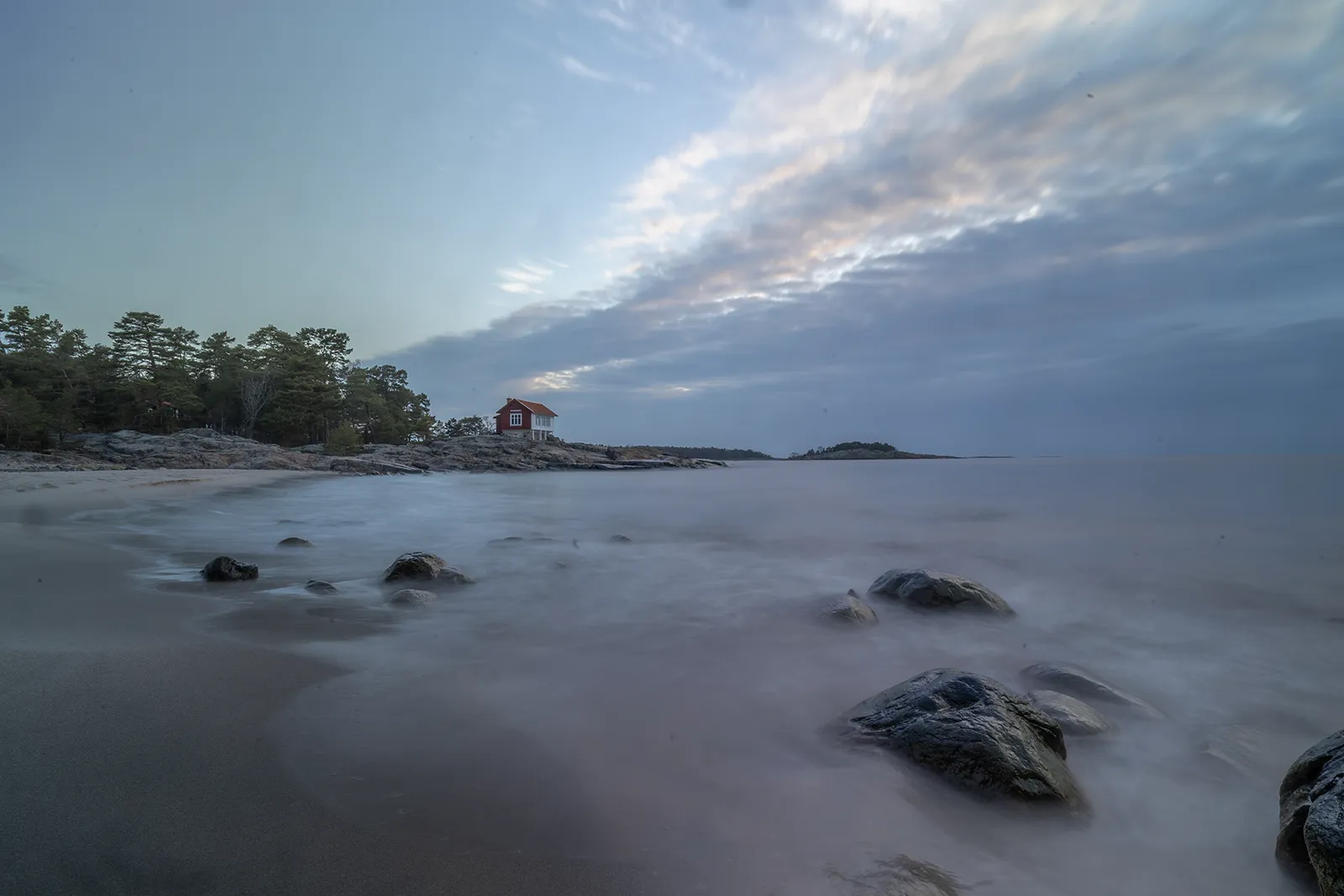 Hav, strand och rött hus